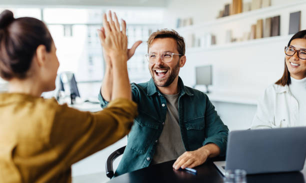 Business partners celebrating successful registration in the IFZA Free Zone with a high-five in an office.