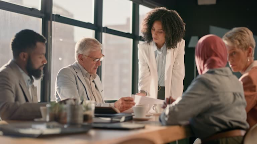 A diverse group of business professionals discuss IFZA Free Zone license fees in a modern office setting.